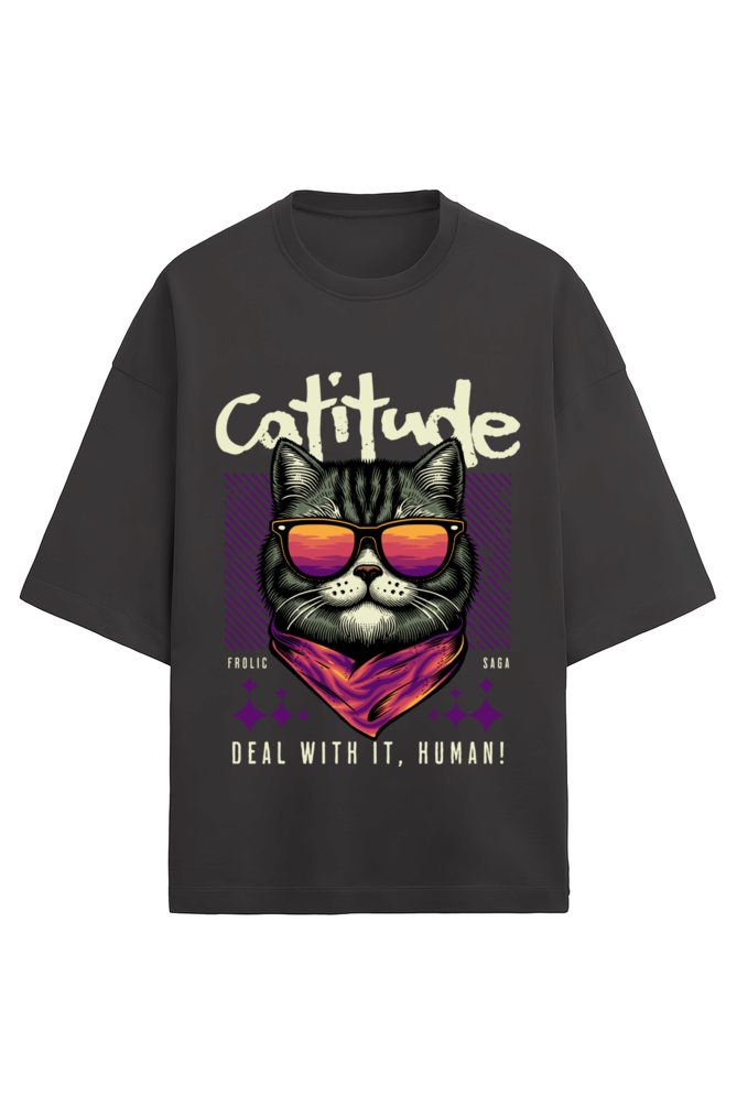 A black oversized unisex t-shirt with a graphic of a cat wearing sunglasses and a bandana, with the words "Cattitude" in bold above and "Deal With It, Human!" below, designed by Frolic Saga.