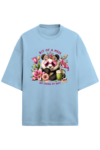 An oversized white French Terry tee in 280 GSM with a colorful print of a panda wearing pink sunglasses and a floral crown, surrounded by flowers and a smoothie. The text reads "BIT OF A MESS BUT DOING MY BEST."