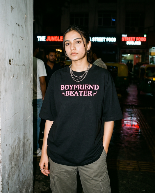 Person wearing a black t-shirt with 'BOYFRIEND + BEATER' text in an urban night setting.