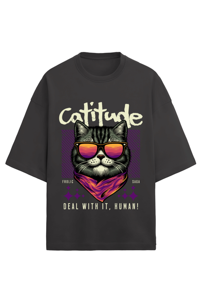 A black oversized unisex t-shirt with a graphic of a cat wearing sunglasses and a bandana, with the words "Cattitude" in bold above and "Deal With It, Human!" below, designed by Frolic Saga.
