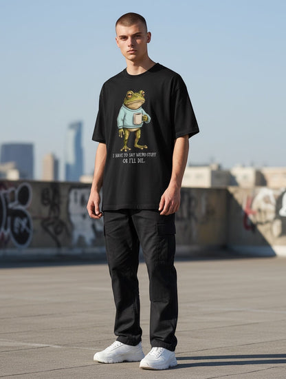 Frolic Saga black oversized cotton t-shirt with a graphic of a frog wearing a sweater and holding a mug, text reads "I HAVE TO SAY WEIRD STUFF OR I'LL DIE."