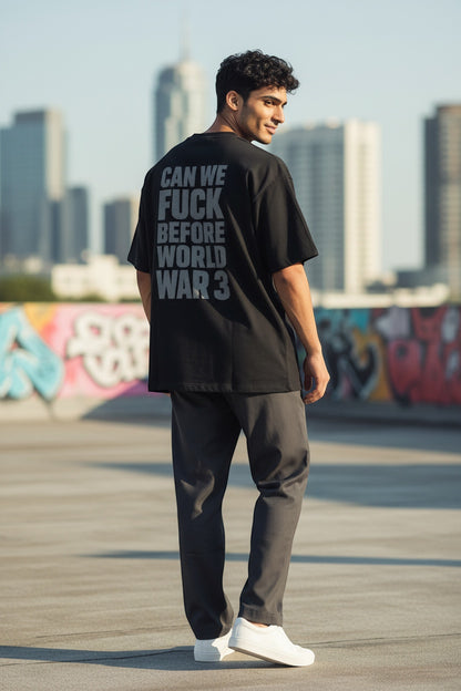 Frolic Saga black oversized 100% cotton t-shirt with bold grey text graphic on back: CAN WE FUCK BEFORE WORLD WAR 3.