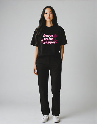 Frolic Saga black 100% cotton oversized t-shirt with pink "born to be a yapper" graphic and microphone icon.