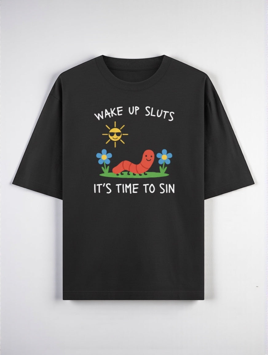 Frolic Saga black 100% cotton oversized t-shirt with a graphic print of a smiling worm, sun, and flowers. Text reads "WAKE UP SLUTS IT'S TIME TO SIN."