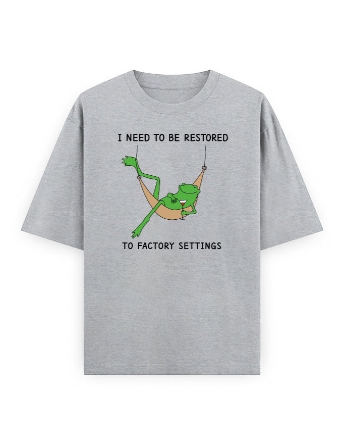 Frolic Saga grey 100% cotton oversized t-shirt with a graphic of a frog relaxing in a hammock and text that reads "I NEED TO BE RESTORED TO FACTORY SETTINGS".