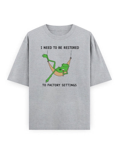 Frolic Saga grey 100% cotton oversized t-shirt with a graphic of a frog relaxing in a hammock and text that reads "I NEED TO BE RESTORED TO FACTORY SETTINGS".