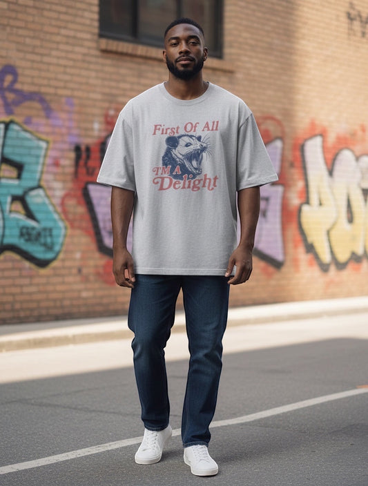 Frolic Saga light grey 100% cotton oversized t-shirt with a graphic print of an opossum and text that reads "First Of All I'm A Delight".