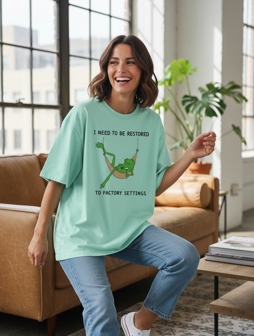 Frolic Saga mint green 100% cotton oversized t-shirt with a graphic of a frog in a hammock and text "I NEED TO BE RESTORED TO FACTORY SETTINGS".