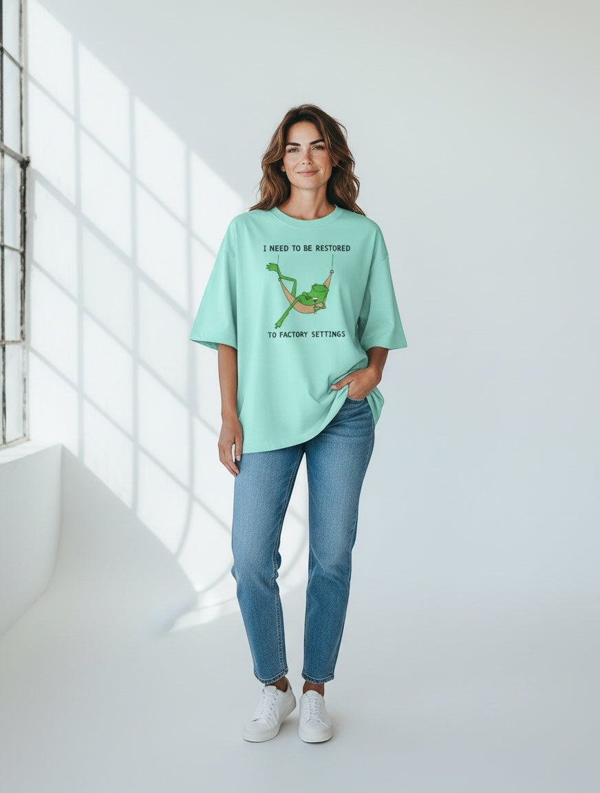 Frolic Saga unisex oversized mint green 100% cotton t-shirt with a graphic print of a frog in a hammock.