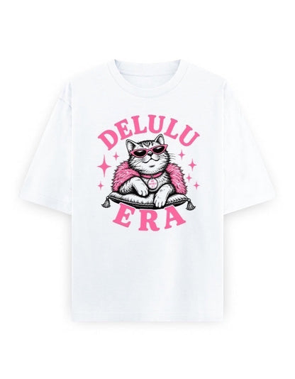 Frolic Saga white 100% cotton oversized t-shirt with a graphic of a cat wearing sunglasses and a pink fluffy boa, sitting on a pillow. Text reads DELULU ERA.