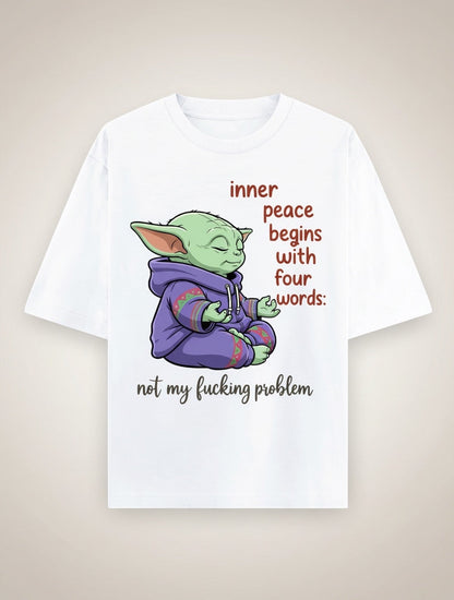 Frolic Saga white 100% cotton oversized t-shirt with a graphic of a green character meditating, wearing a purple hoodie. Text reads "inner peace begins with four words: not my fucking problem."