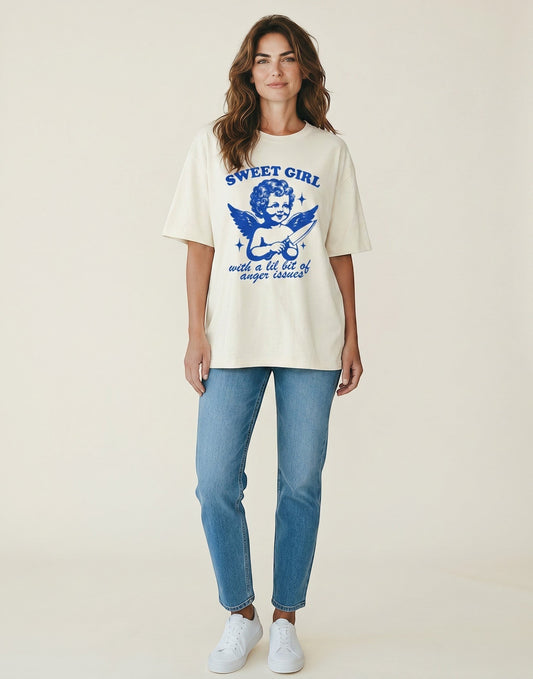 Woman wearing a Frolic Saga cream oversized cotton t-shirt with a blue graphic of a cherub holding a knife.