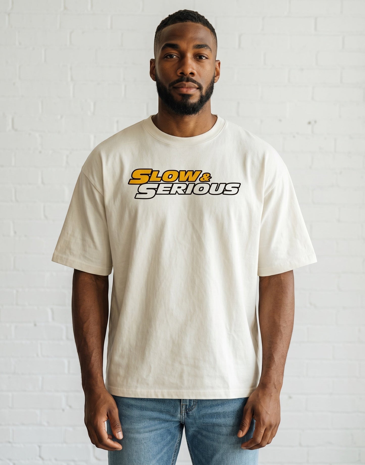 Frolic Saga unisex oversized cream cotton t-shirt with Slow & Serious graphic print worn by a man.