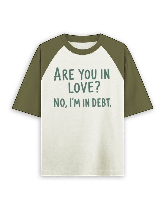 Cream and olive green oversized raglan t-shirt featuring the dark green text ARE YOU IN LOVE? NO, I'M IN DEBT.