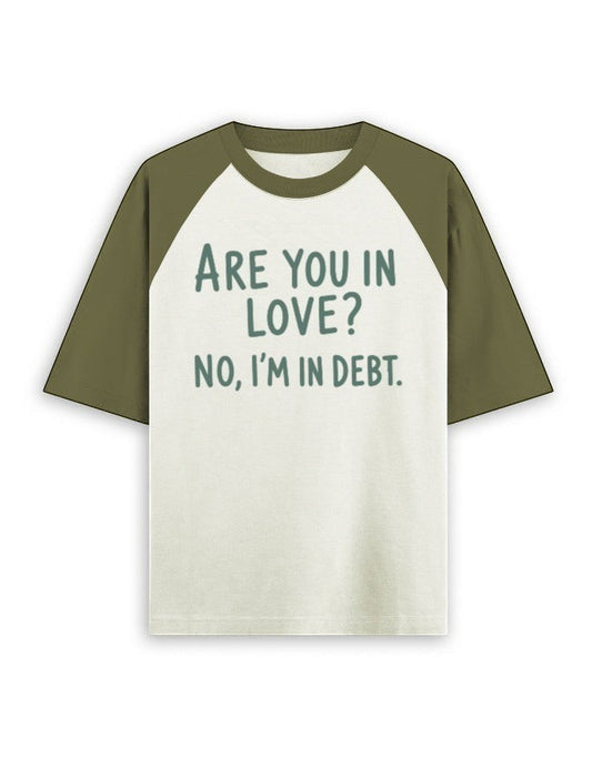 Cream and olive green oversized raglan t-shirt featuring the dark green text ARE YOU IN LOVE? NO, I'M IN DEBT.