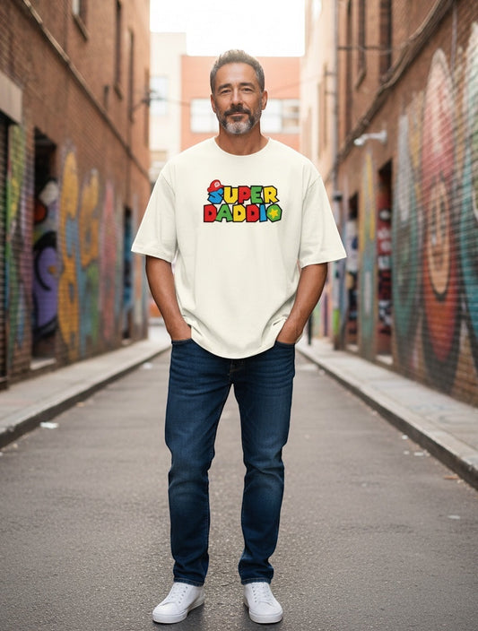 Frolic Saga unisex oversized cream t-shirt with "SUPER DADDIO" graphic print in colorful Mario-style font. 100% cotton.