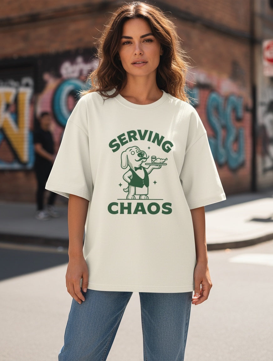 Frolic Saga Unisex oversized classic t-shirt in cream, 100% cotton with a dog graphic and "SERVING CHAOS" text.