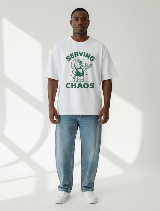Frolic Saga white 100% cotton oversized t-shirt with green 'Serving Chaos' dog graphic. Unisex fit.