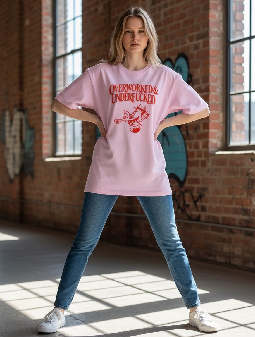 Frolic Saga light pink oversized cotton t-shirt with red "Overworked & Underfucked" graphic and cat illustration.