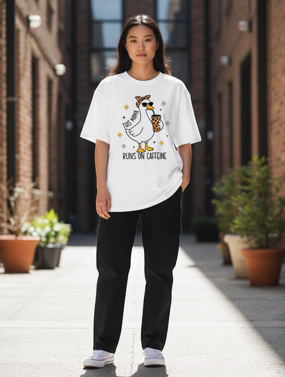 Frolic Saga white 100% cotton oversized t-shirt with a graphic of a duck wearing sunglasses and a bandana, holding a coffee cup. Text reads "This Mama Runs On Caffeine".